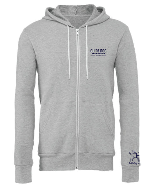  Image description: A soft, grey zip-up sweatshirt with a white zipper running down the front. The sweatshirt has white drawstrings for the hood and features the navy Guide Dog Foundation logo embroidered on the left chest. Additionally, the Guide Dog Foundation logo, depicting a guide dog, is present on the left sleeve, accompanied by the "GuideDog.org" URL written underneath in a clear, legible font.